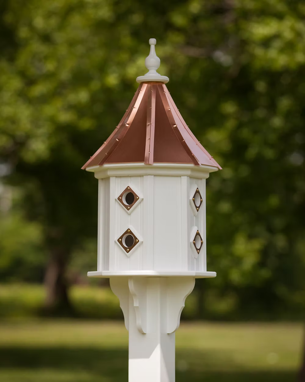 White birdhouse with a brown roof against a green outdoor background